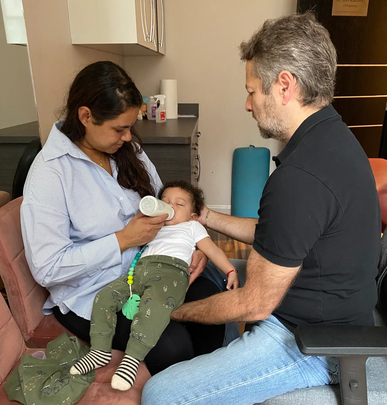Mother bottle-feeding her baby as Dr. Kaminsky provides gentle craniosacral support.